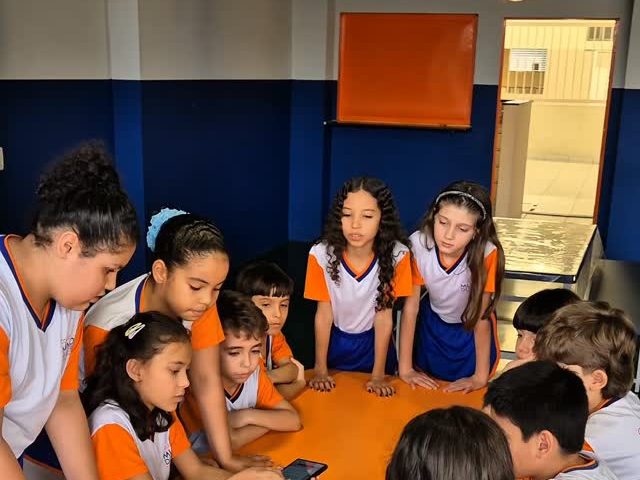 Alunos do 4º e 5º ano reunidos em volta da mesa redonda da sala de aula