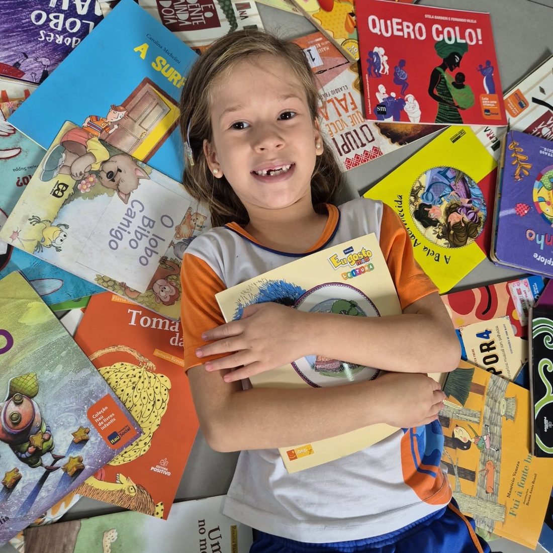 Aluna segurando uma pilha de livros no Dia do Livro Infantil
